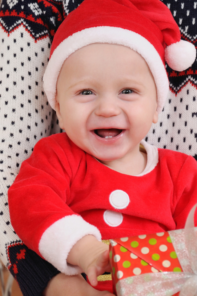 Улыбающийся малыш в костюме с подарком на руках 