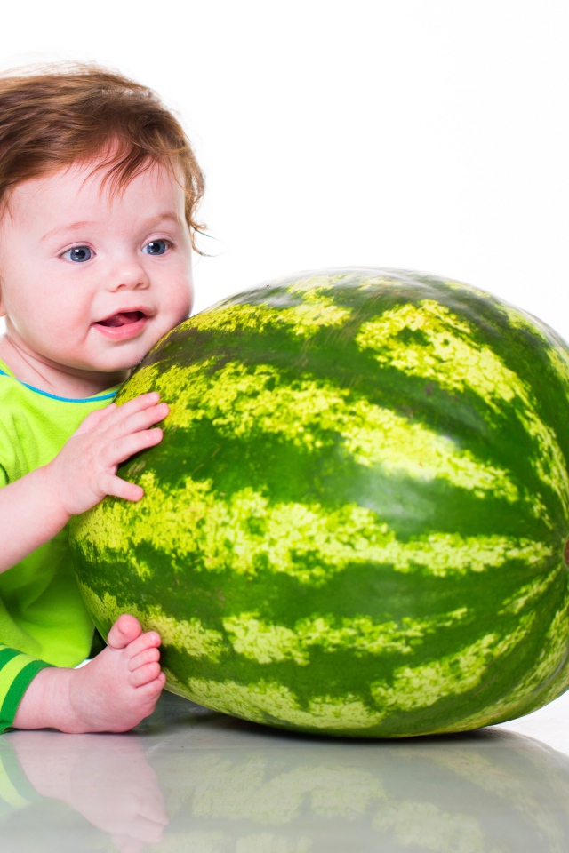 Улыбающийся малыш с большим арбузом на белом фоне