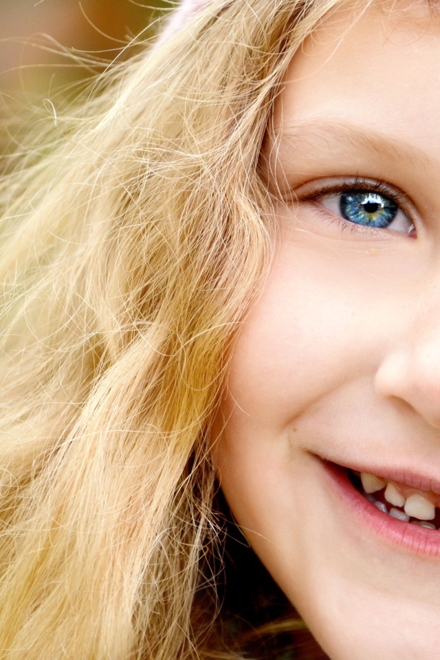 Улыбающаяся светловолосая девочка с голубыми глазами крупным планом