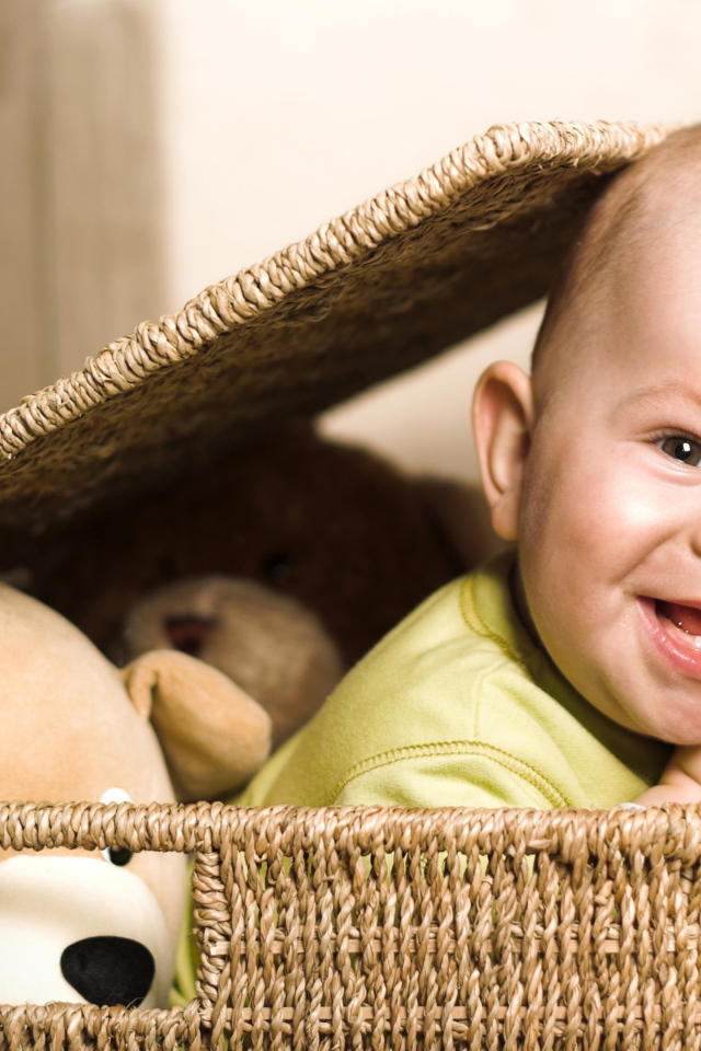 Улыбающийся забавный малыш в плетеной корзине с игрушками