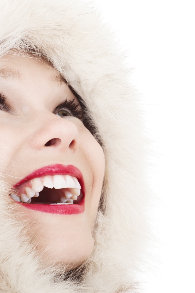 Улыбающаяся девушка в меховом капюшоне на белом фоне