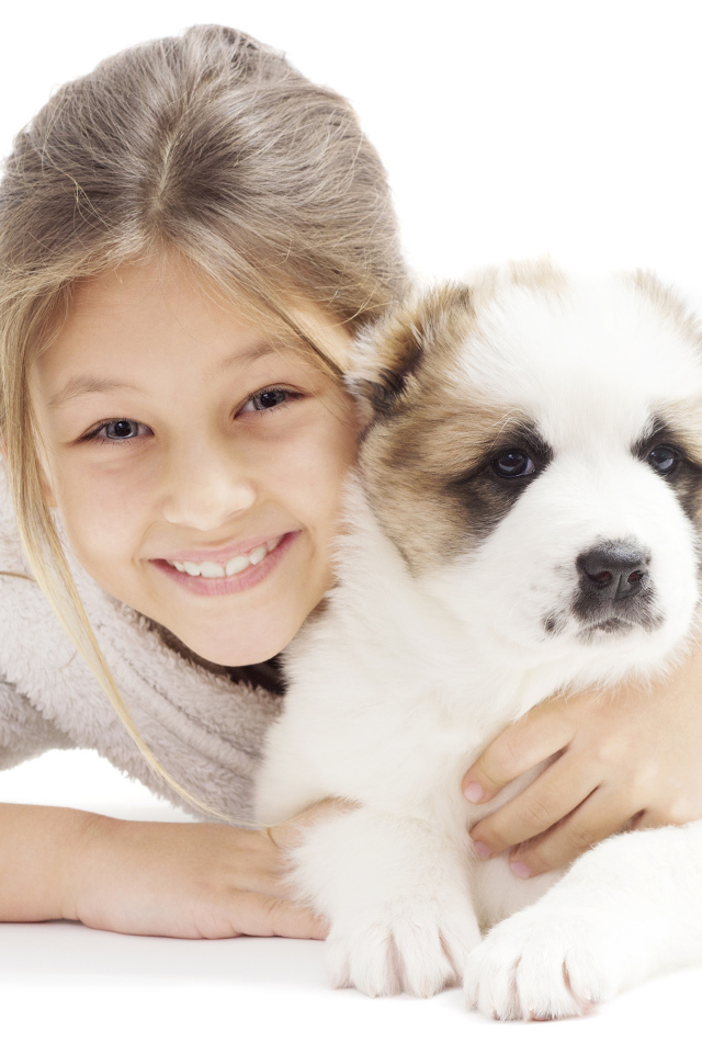 Улыбающаяся девочка лежит с щенком алабая