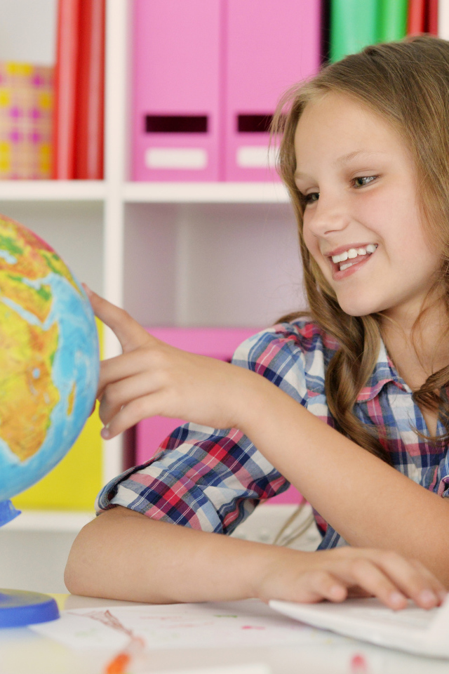 Улыбающаяся девочка школьница с глобусом