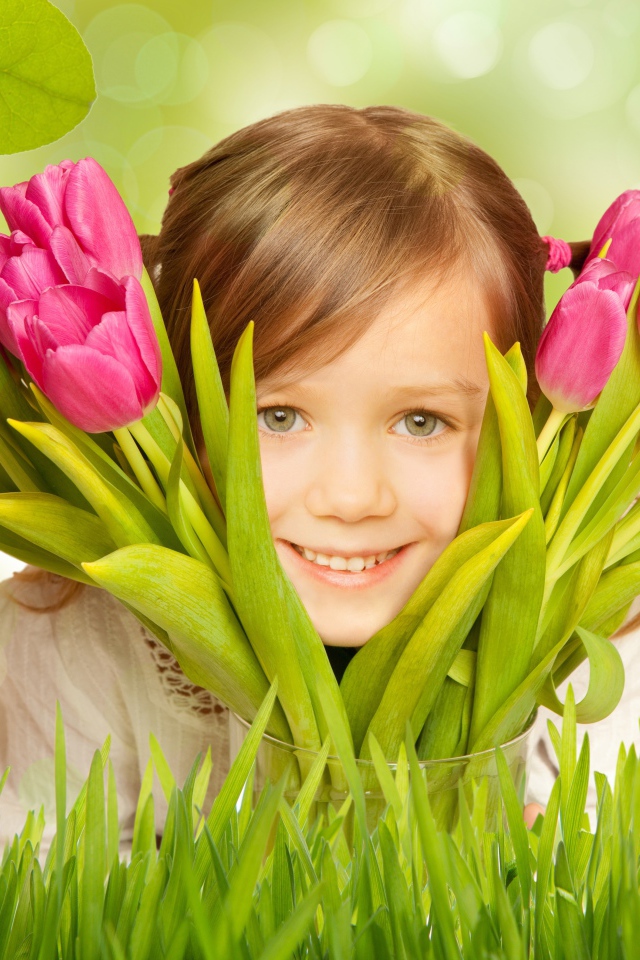 Улыбающаяся маленькая девочка с розовыми тюльпанами