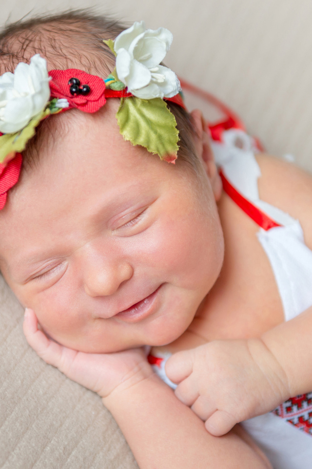 Улыбающаяся спящая девочка с венком на голове