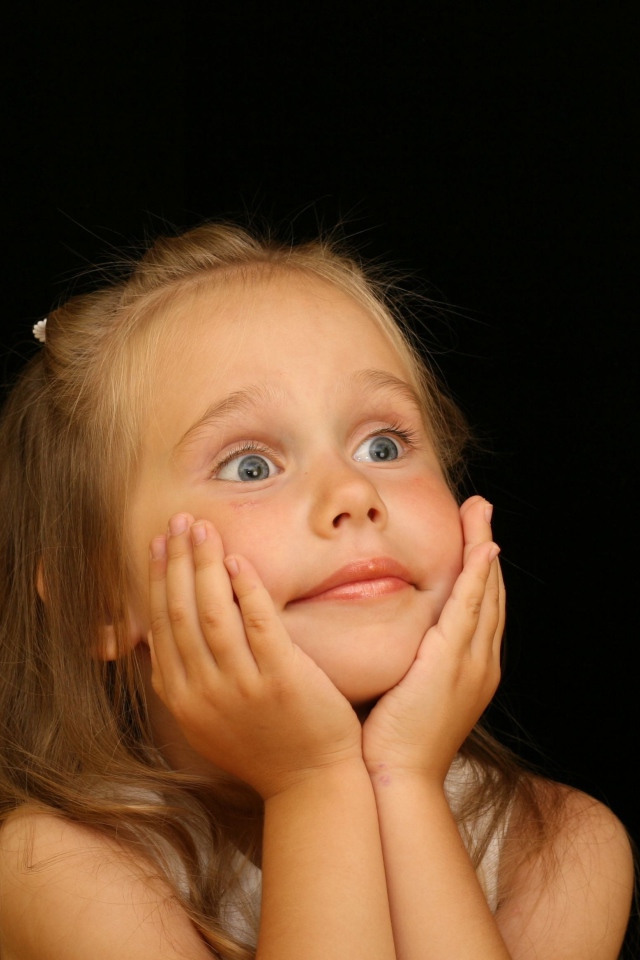 Удивленная маленькая девочка на черном фоне