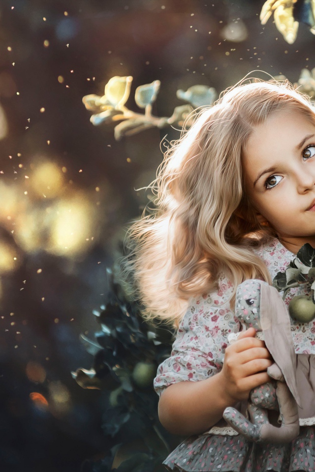 Маленькая девочка стоит у ветки с яблоками