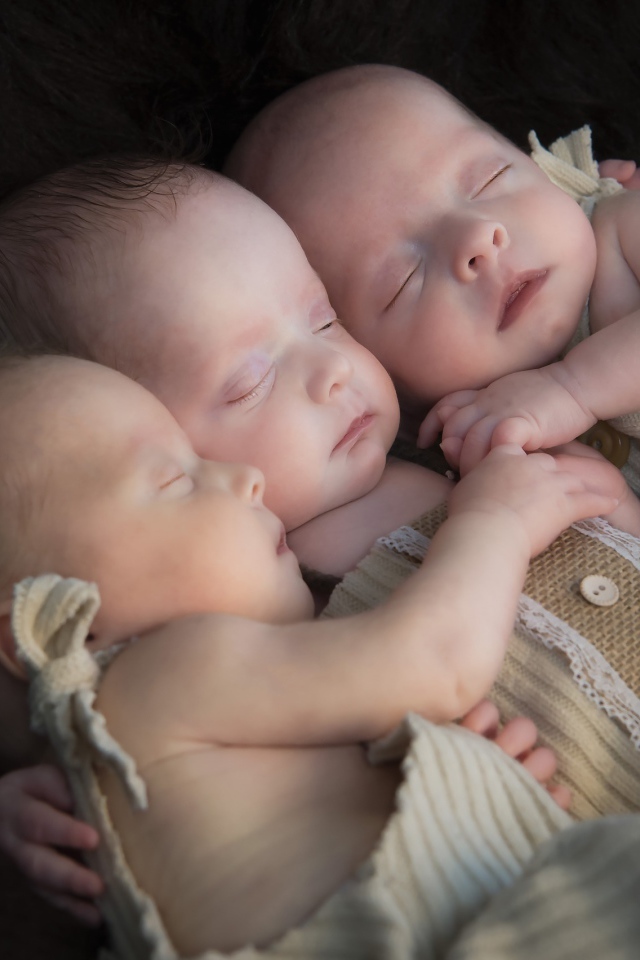Три маленьких грудных ребенка спят обнявшись 