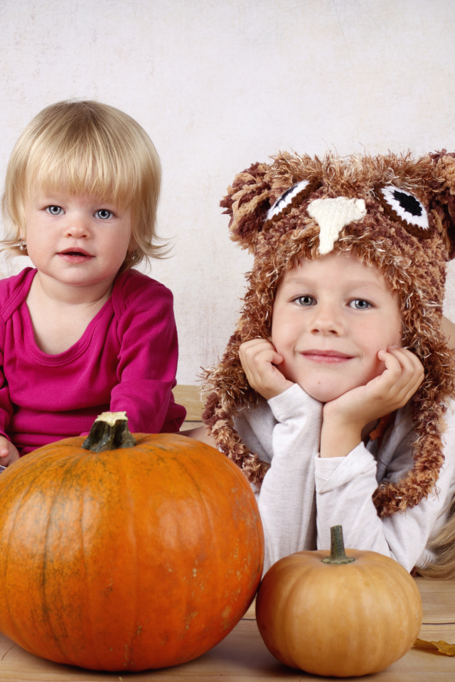 Два маленьких ребенка с тыквами в комнате