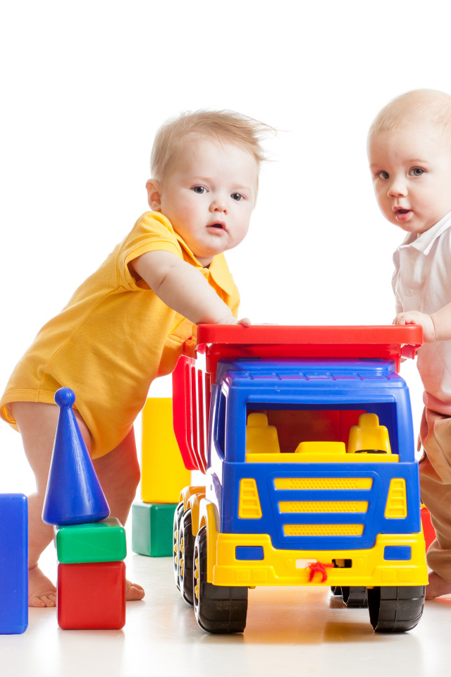 Два маленьких ребенка с игрушками на белом фоне