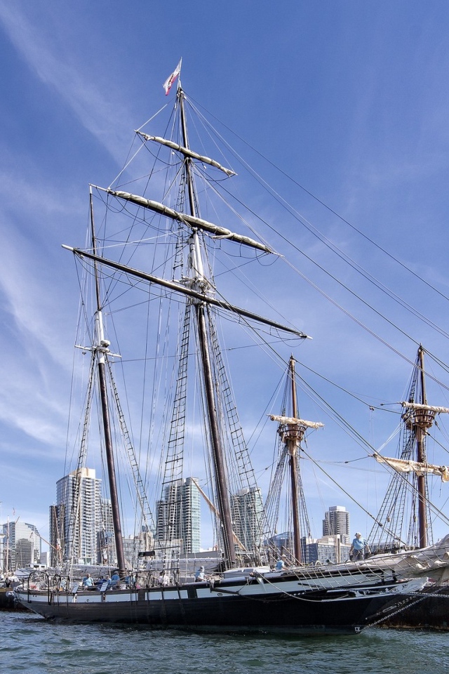 Большая парусная лодка на фоне голубого неба в порту у города