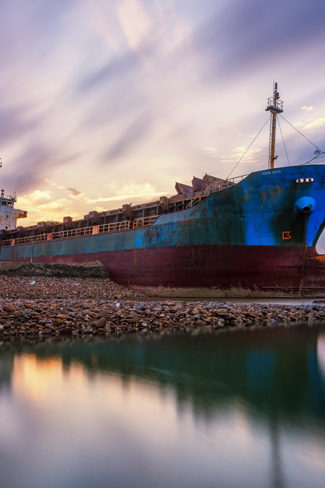 Старый ржавый корабль на берегу под красивым небом