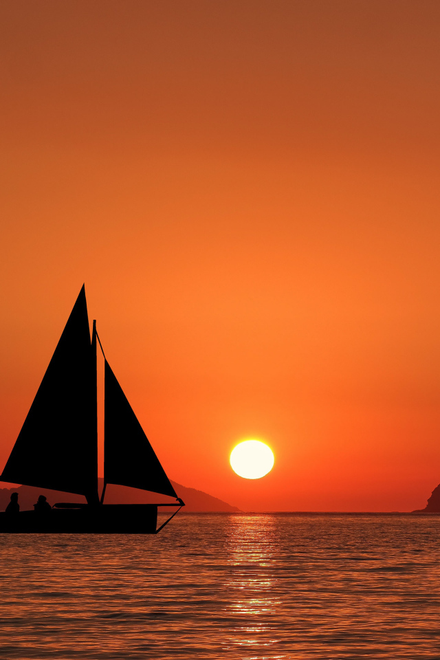 Парусная лодка в море на закате солнца