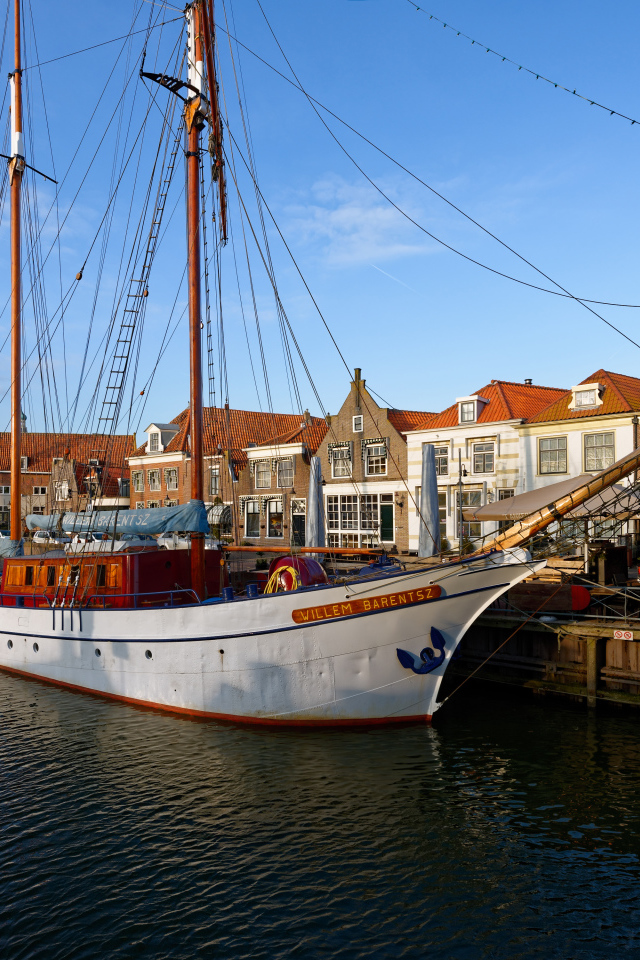 Парусное судно Willem Barentsz с опущенными парусами на причале у домов