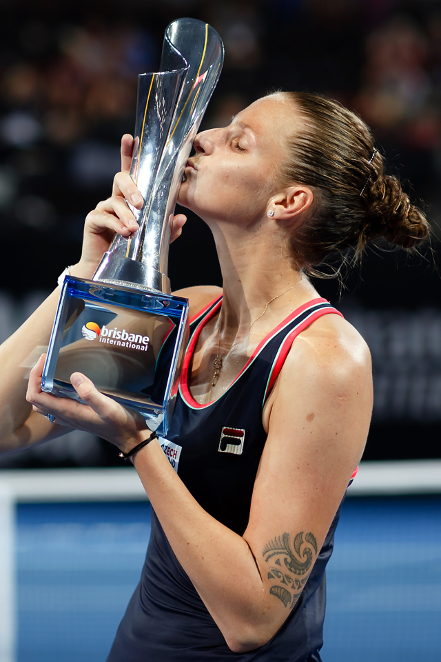 Чешская теннисистка Каролина Плишкова целует кубок на корте