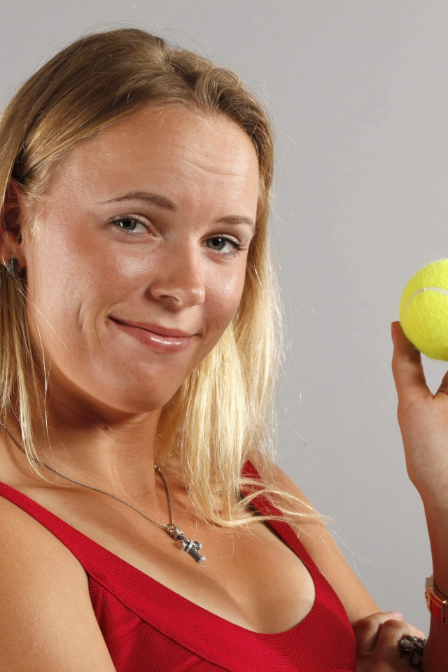 Датская теннисистка Каролина Возняцки с мячиком в руке на сером фоне