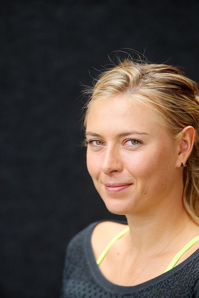 Улыбающаяся блондинка, теннисистка Мария Шарапова на сером фоне