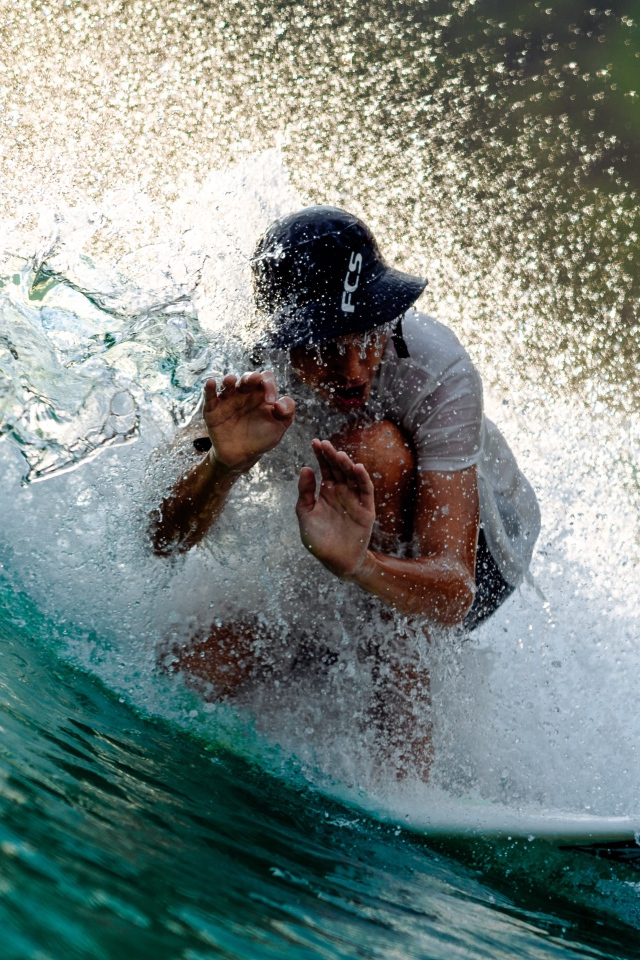 Парень серфингист ловит голубую морскую волну