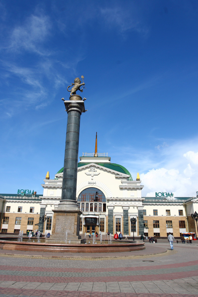 Памятник у здания железнодорожного вокзала под красивым голубым небом, Красноярск. Россия