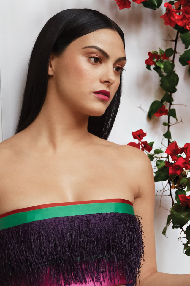 Актриса Камила Мендес стоит у стены с цветами