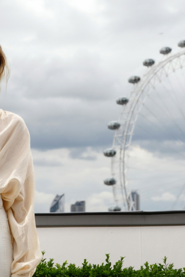 Актриса Марго Робби на  фоне аттракциона  колесо обозрения