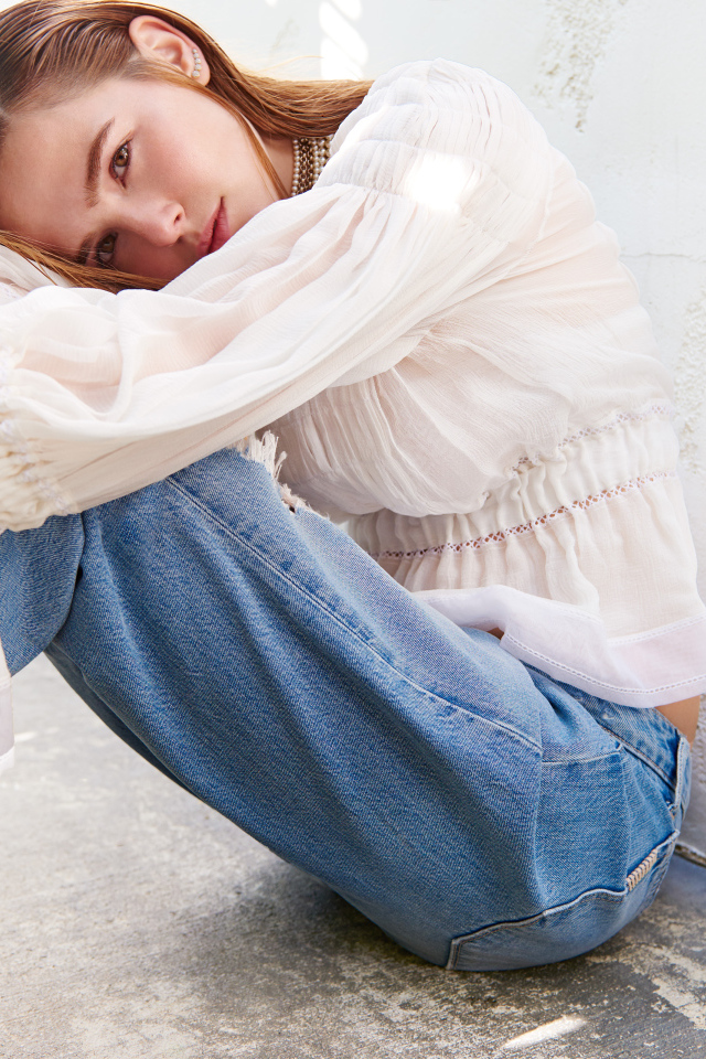 Актриса Зои Дойч сидит у стены