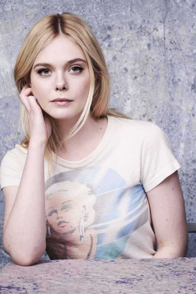 Красивая актриса Эль Фаннинг сидит за столом