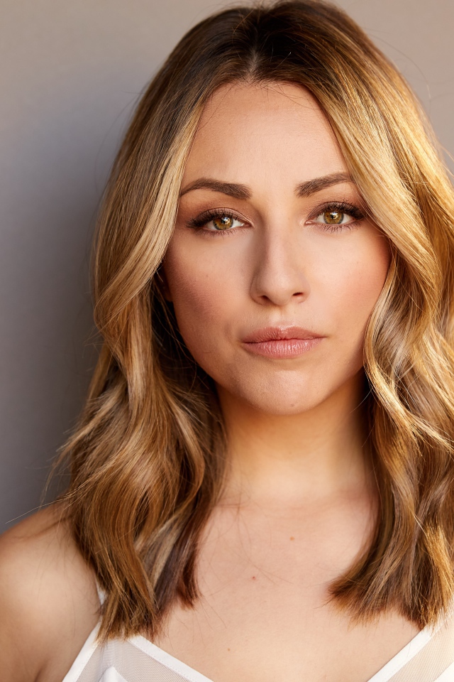 Красивая блондинка Никки Поснер на сером фоне 