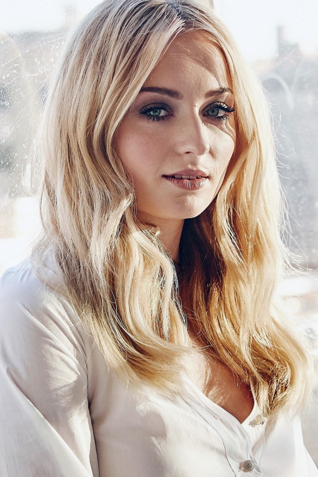 Красивая зеленоглазая блондинка, актриса Софи Тёрнер у окна