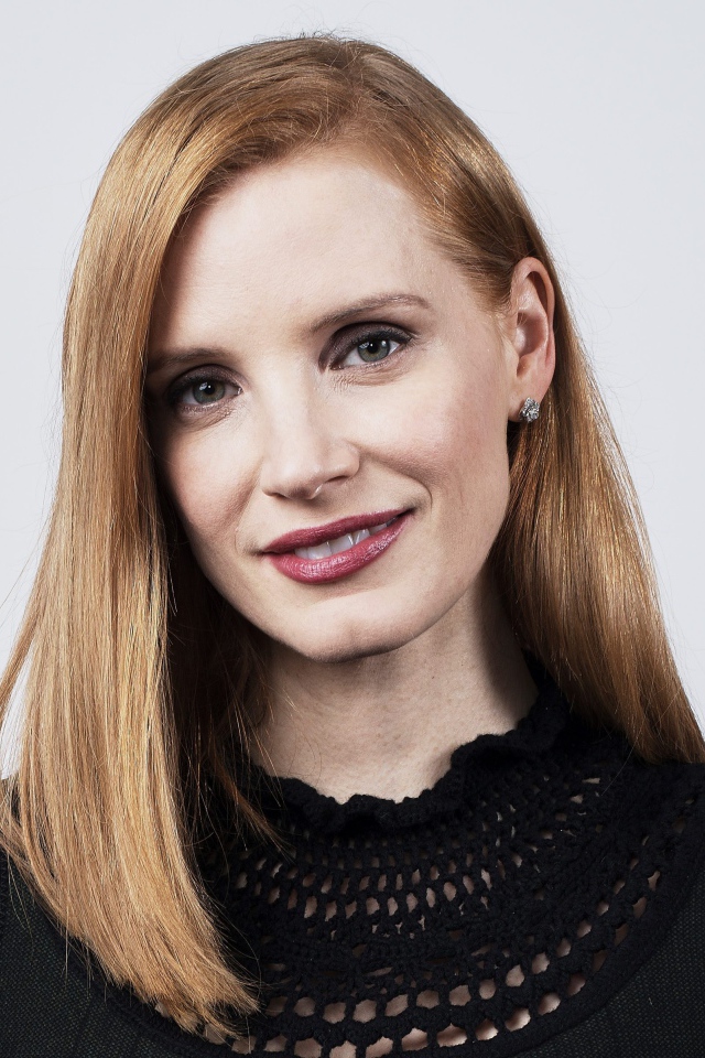 Красивая рыжеволосая актриса Джессика Честейн на сером фоне