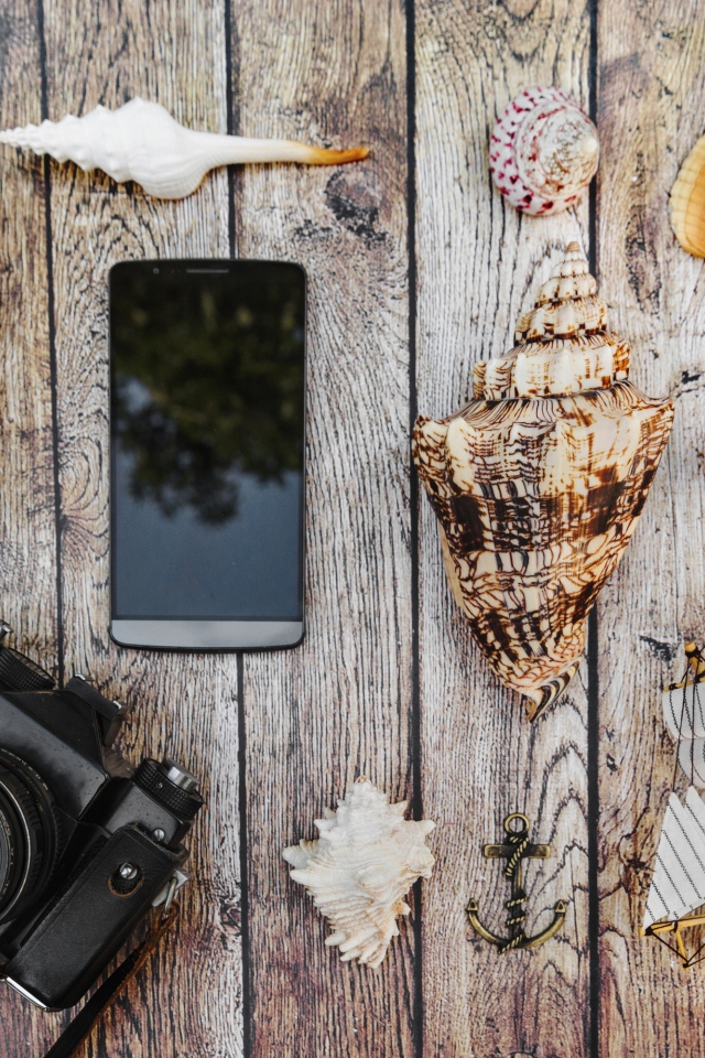 Camera, smartphone, shells, glasses and passport on the table