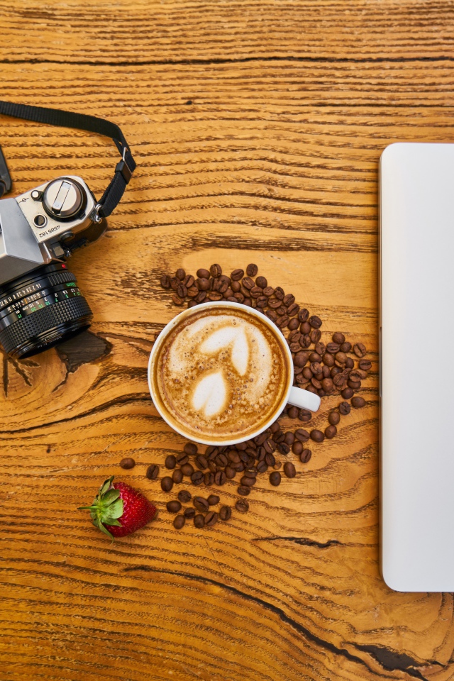 Чашка кофе на столе с фотоаппаратом и ноутбуком