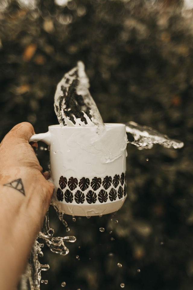 Чашка с водой в руке с татуировкой 