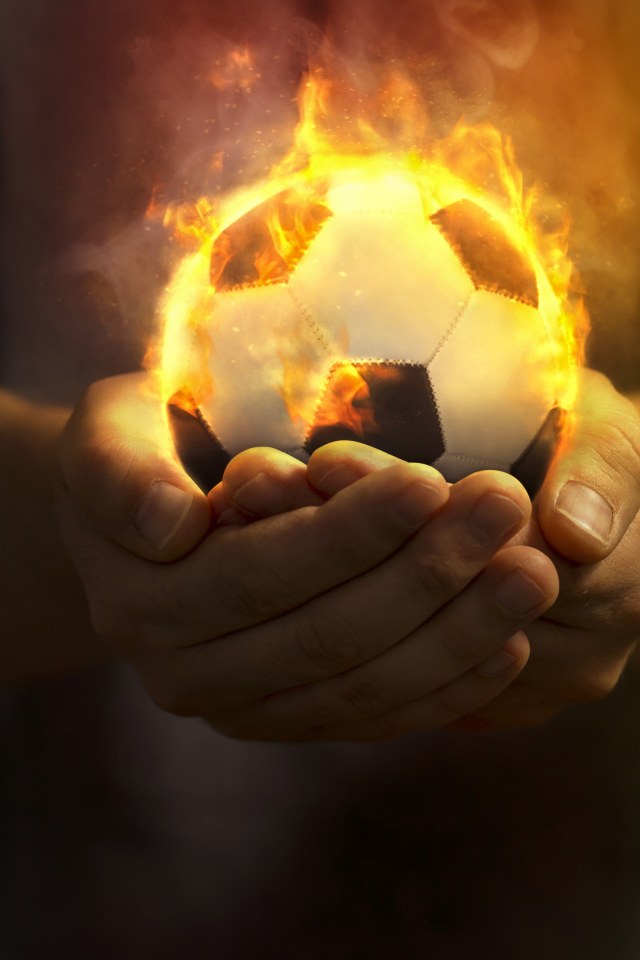 Огненный футбольный мяч в руках 
