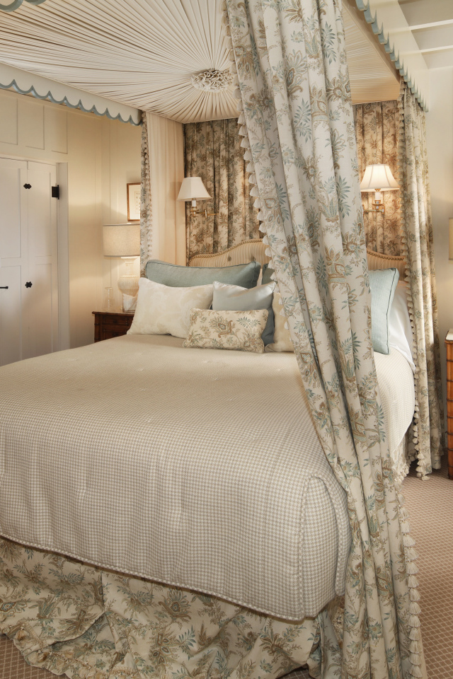 Высокая кровать с занавесками в спальной комнате в пастельных тонах 