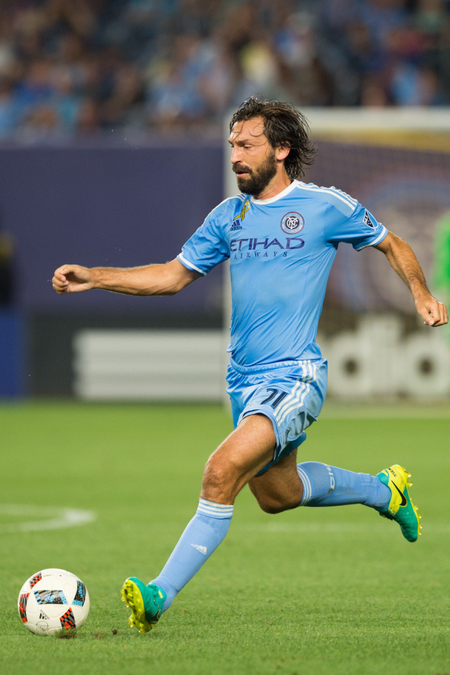 Итальянский футболист Андреа Пирло отбивает мяч на футбольном поле