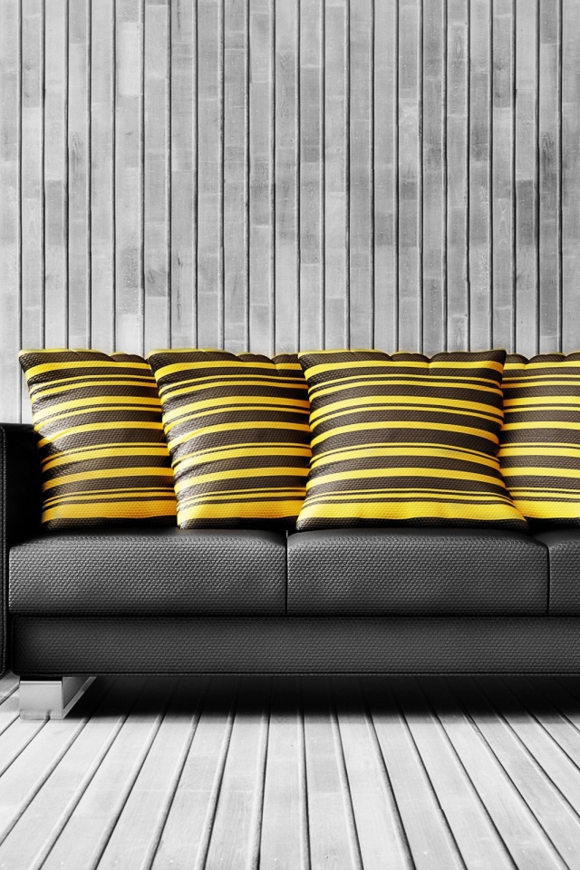 Большой черный кожаный диван с подушками у стены