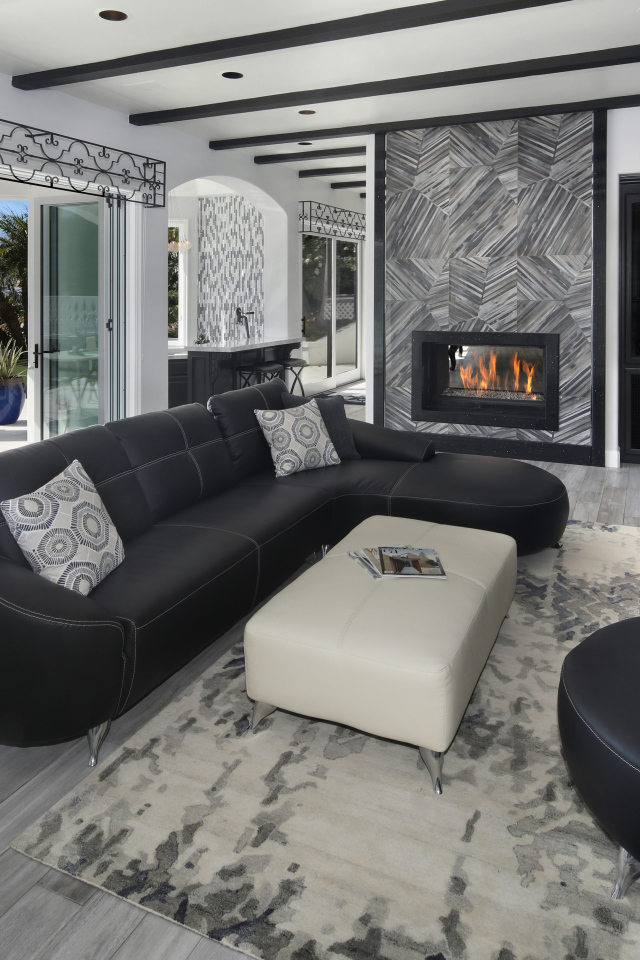 Большая просторная гостиная с черными кожаными диванами, телевизором и камином 