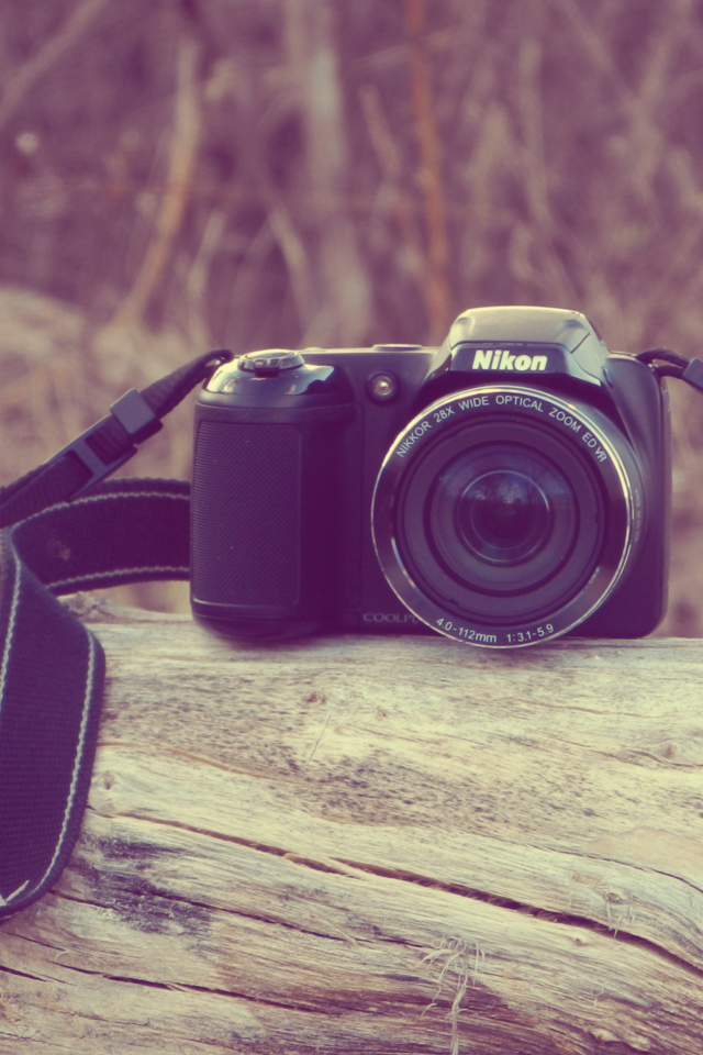 Фотоаппарат Nikon лежит на сухом дереве