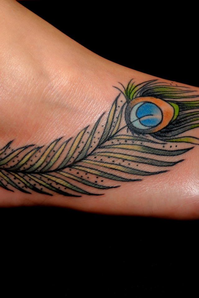 Peacock feather tattoo on leg on black background