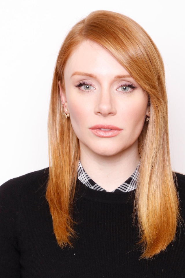 Рыжеволосая актриса Брайс Даллас Ховард в черном свитере на белом фоне