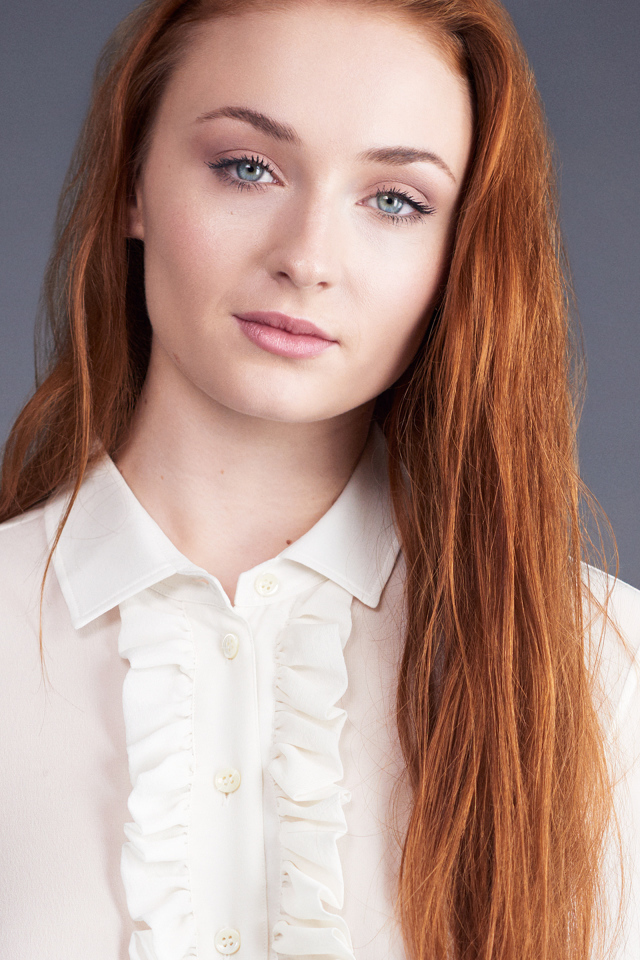 Рыжеволосая голубоглазая актриса Софи Тёрнер на сером фоне