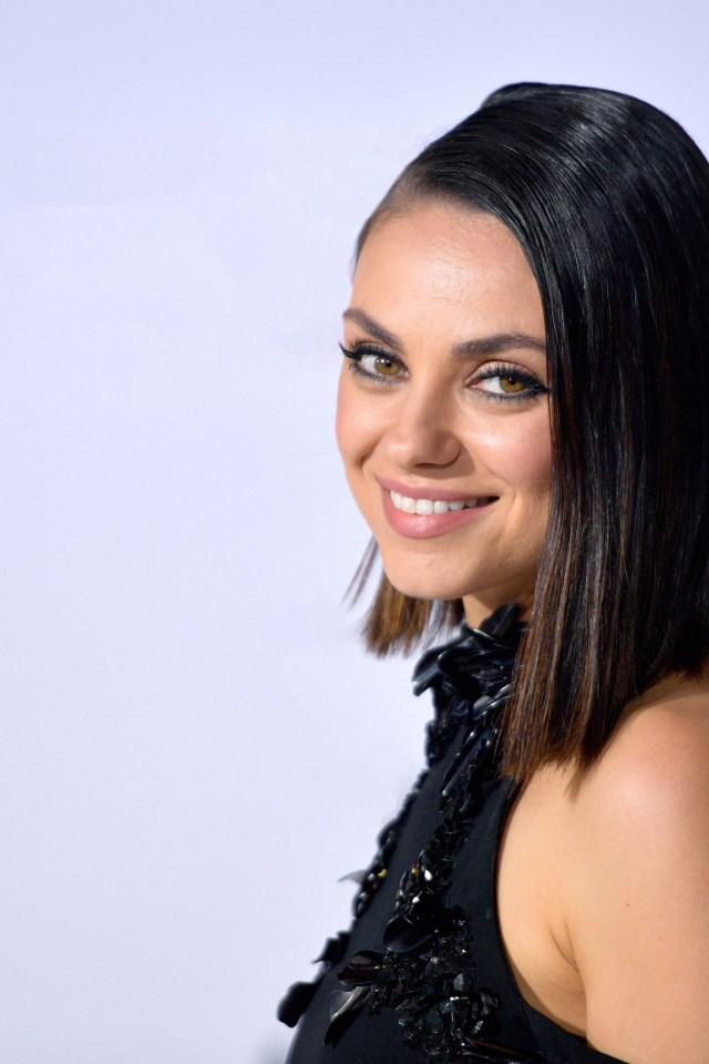 Улыбающаяся красивая девушка, актриса Мила Кунис на сером фоне