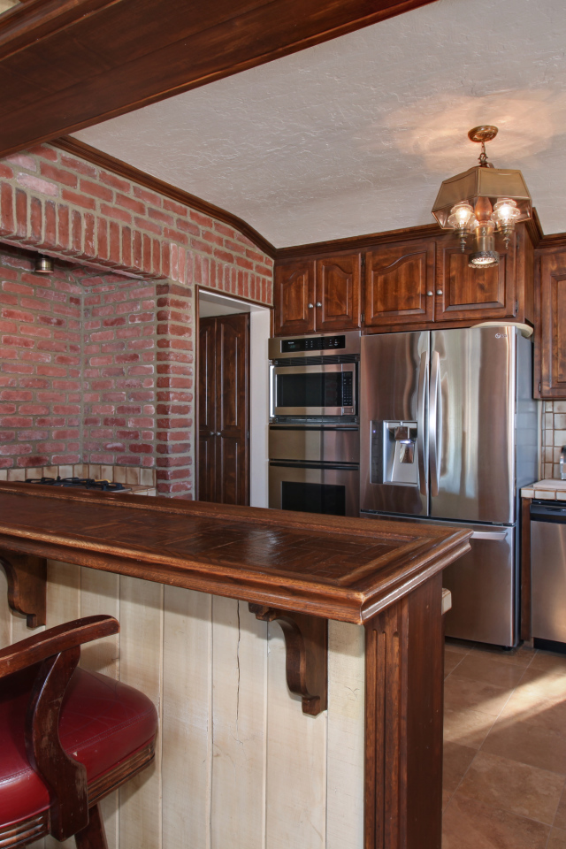 Просторная кухня с деревянной мебелью и кожаными стульями