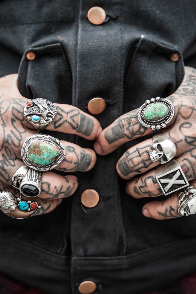 Татуировки на руках мужчины с перстнями