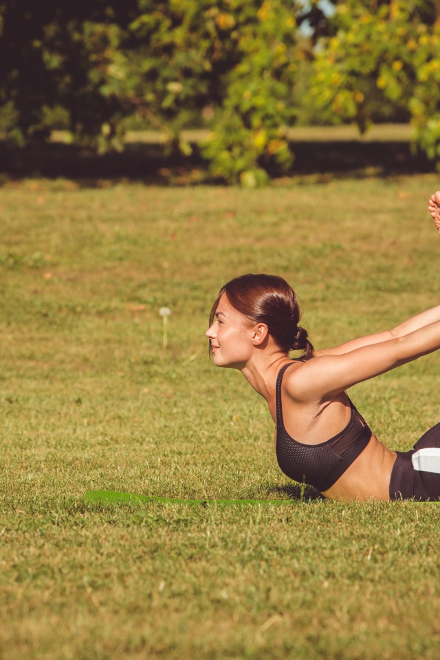 Девушка занимается гимнастикой на зеленой траве