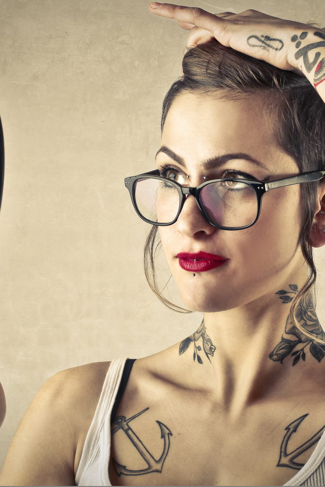 Девушка с татуировками на теле смотрит в зеркало