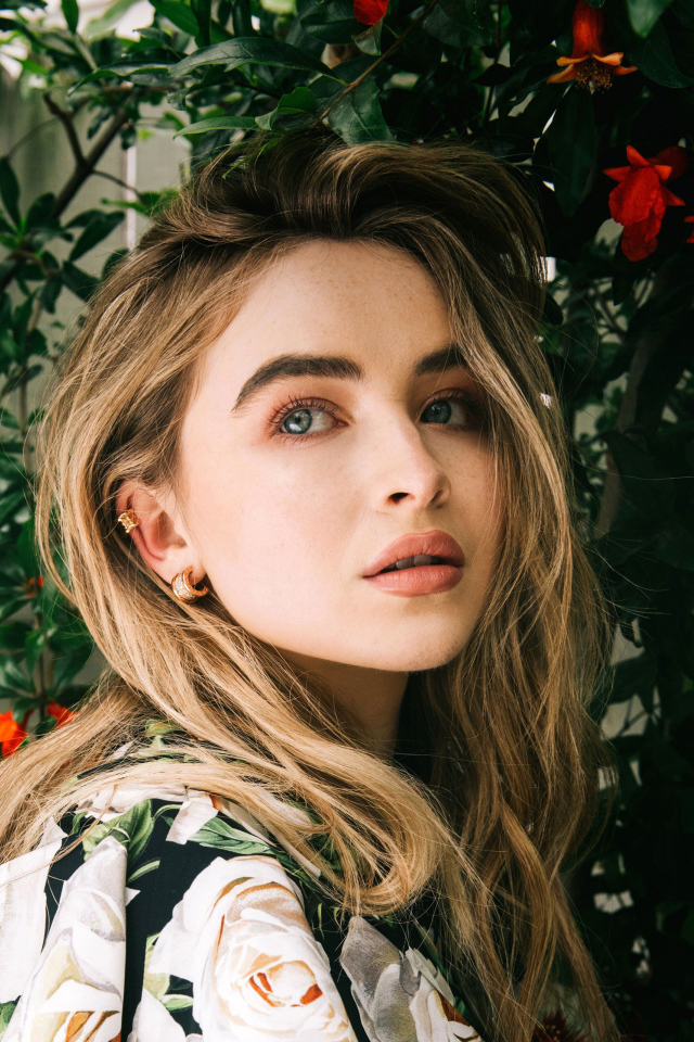 Молодая красивая актриса Сабрина Карпентер у красных цветов