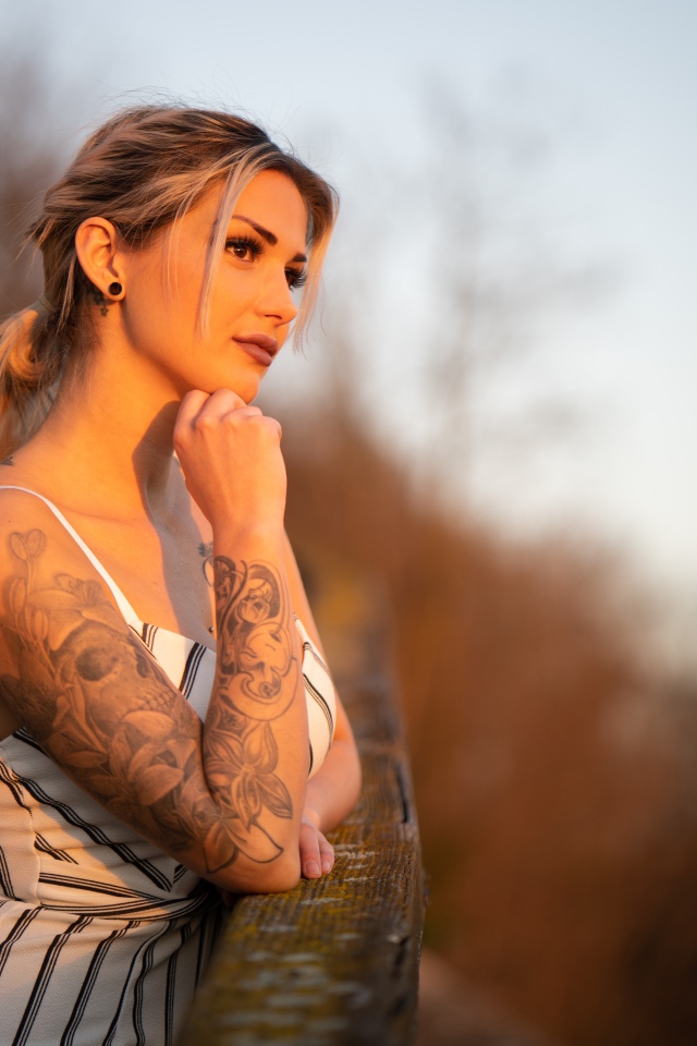 Молодая девушка с татуировкой на руке в лучах солнца