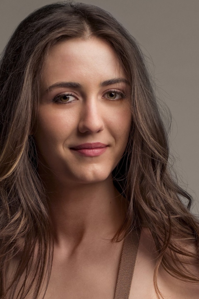 Молодая длинноволосая девушка, актриса Мэйделин Зима на сером фоне